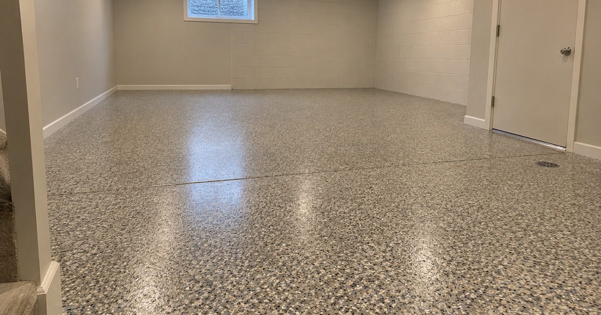 An empty finished flake floor in a Des Plaines basement family room, seen from the foot of the stair.